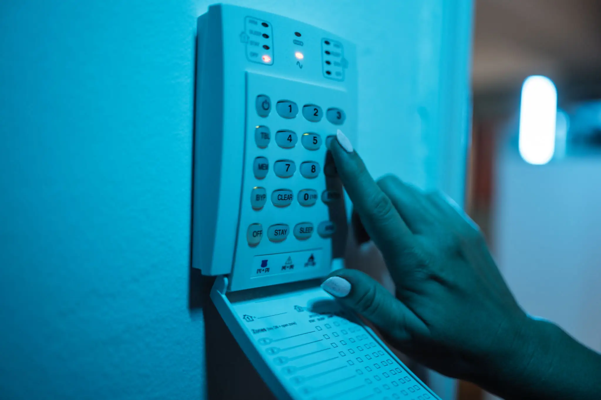 Hand entering code on security alarm keypad