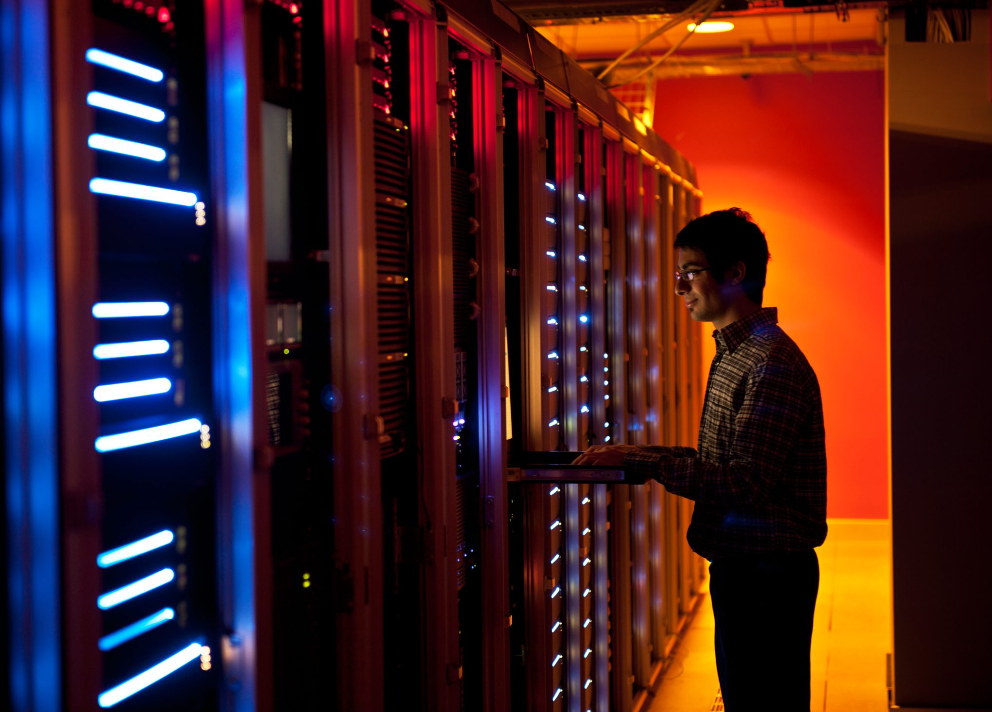 Technician working on laptop in server room