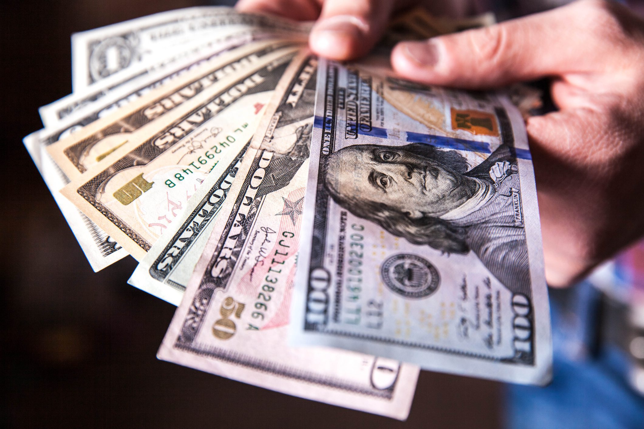 Hand holding fanned US dollar bills